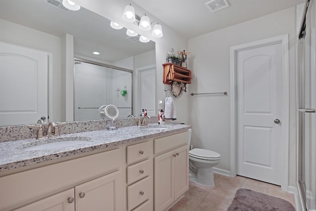 bathroom with a shower with door, vanity, tile patterned floors, and toilet