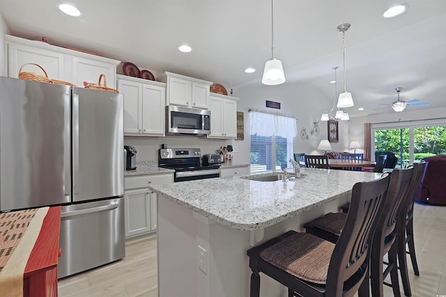 kitchen with stainless steel appliances, an island with sink, hanging light fixtures, and white cabinets