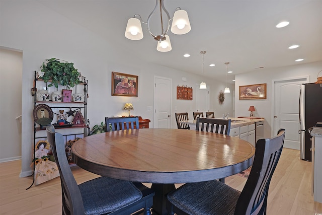 dining space with sink, an inviting chandelier, and light wood-type flooring