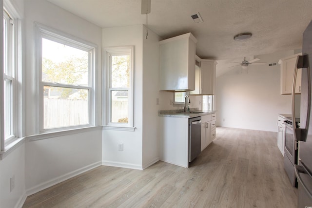 kitchen with sink, light hardwood / wood-style flooring, ceiling fan, appliances with stainless steel finishes, and white cabinetry