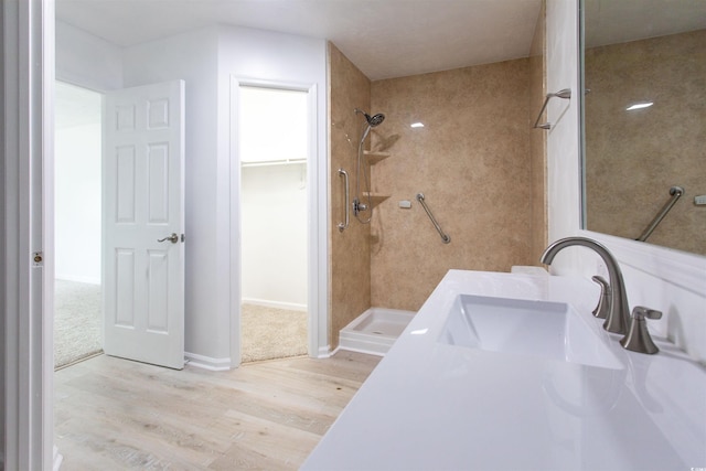 bathroom with a tile shower, sink, and hardwood / wood-style floors