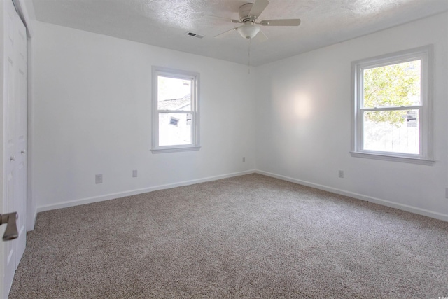 spare room with a healthy amount of sunlight, carpet flooring, ceiling fan, and a textured ceiling