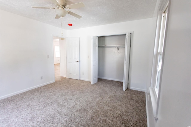 unfurnished bedroom with ceiling fan, carpet, a textured ceiling, and a closet