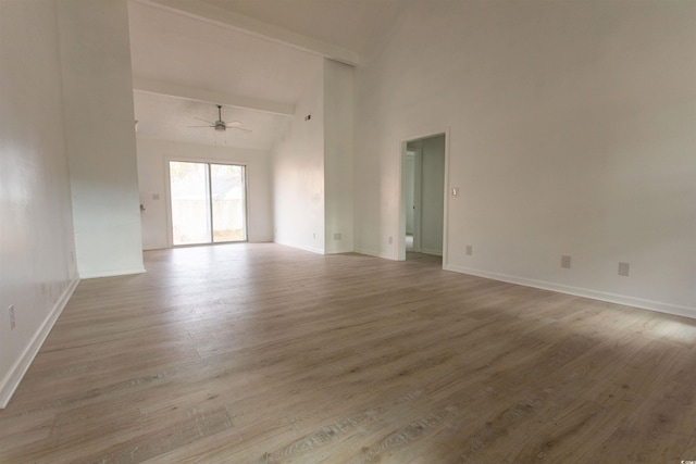 unfurnished room featuring a towering ceiling, light hardwood / wood-style floors, and ceiling fan