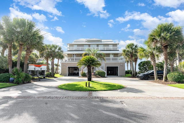 view of front of property featuring a garage, curved driveway, and a balcony