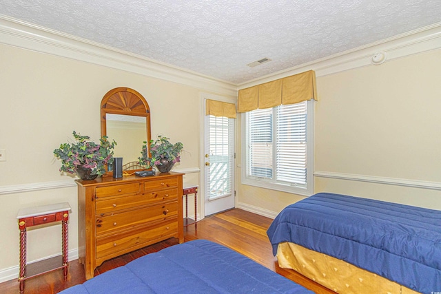 bedroom featuring crown molding, hardwood / wood-style floors, and a textured ceiling