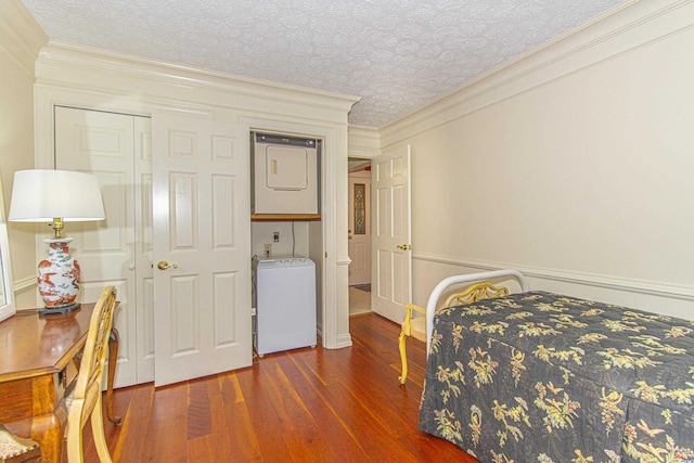 bedroom featuring crown molding, dark wood-type flooring, a textured ceiling, and stacked washer / dryer