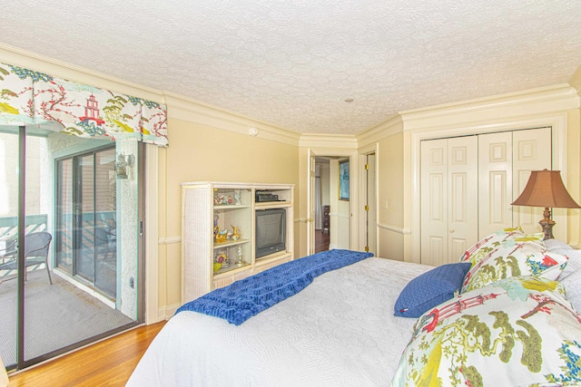 bedroom with hardwood / wood-style flooring, ornamental molding, access to outside, and a closet