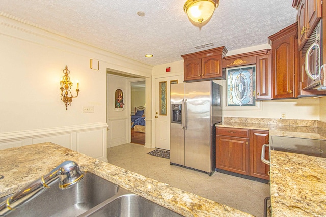 kitchen featuring appliances with stainless steel finishes, sink, light tile patterned floors, and a textured ceiling