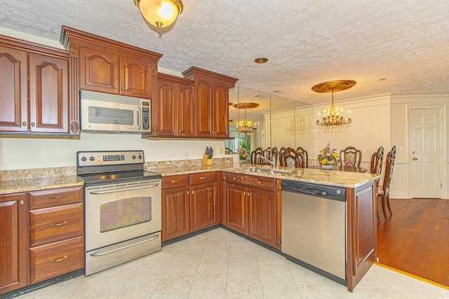 kitchen with decorative light fixtures, sink, a chandelier, kitchen peninsula, and stainless steel appliances