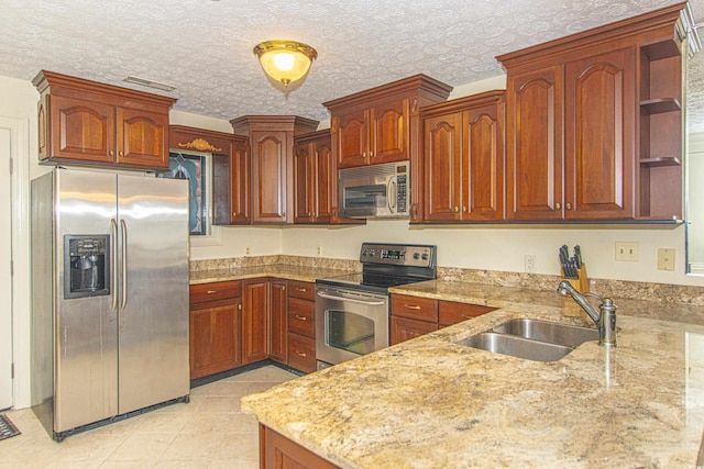 kitchen with sink, a textured ceiling, light tile patterned floors, appliances with stainless steel finishes, and kitchen peninsula