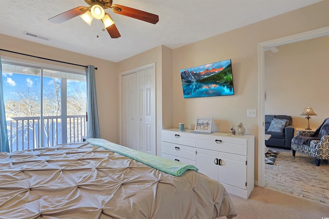 bedroom featuring light colored carpet, a closet, a textured ceiling, and access to outside