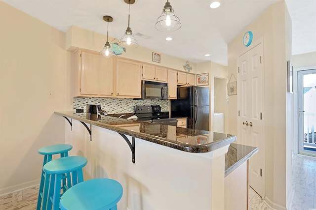 kitchen with light brown cabinetry, tasteful backsplash, black appliances, a kitchen bar, and kitchen peninsula