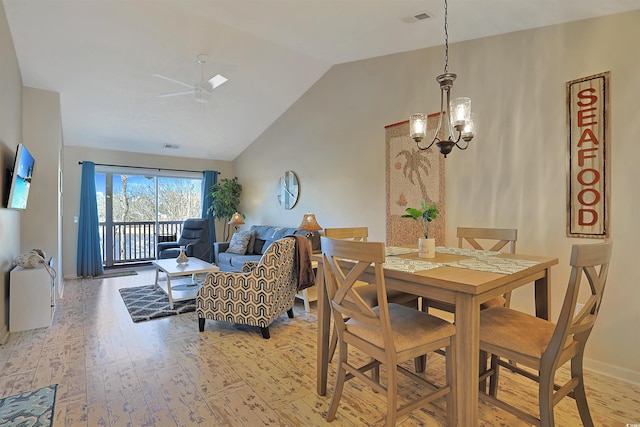 dining area with ceiling fan with notable chandelier, light hardwood / wood-style flooring, and high vaulted ceiling