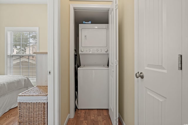 laundry room with stacked washer and dryer and wood-type flooring