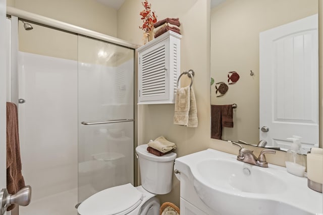 bathroom featuring a shower with door, vanity, and toilet