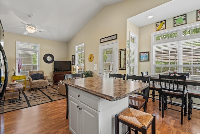 kitchen featuring lofted ceiling, a breakfast bar area, light hardwood / wood-style flooring, white cabinetry, and a kitchen island