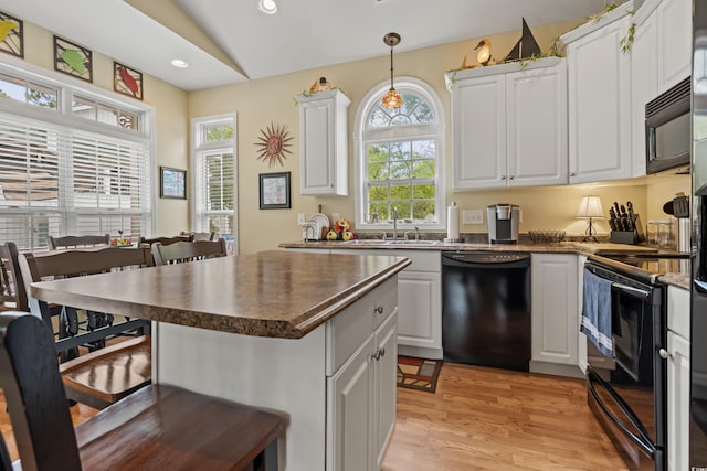 kitchen featuring sink, white cabinets, hanging light fixtures, a center island, and black appliances