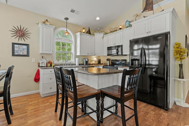 kitchen with pendant lighting, lofted ceiling, white cabinets, black appliances, and light wood-type flooring