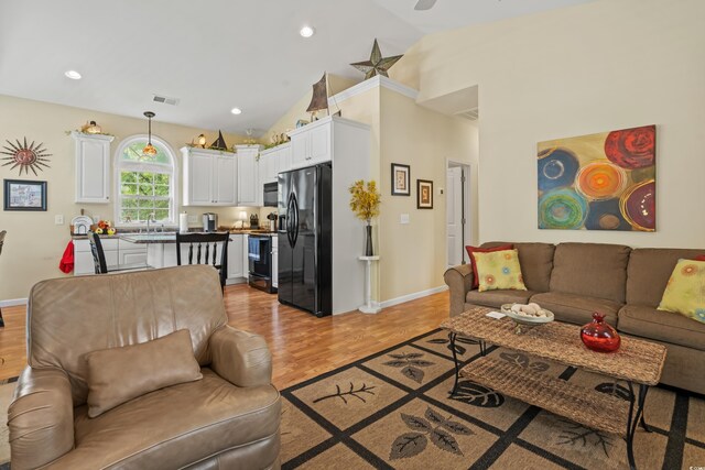 living room with high vaulted ceiling and light wood-type flooring
