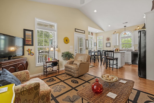 living room featuring high vaulted ceiling, a wealth of natural light, and light hardwood / wood-style floors