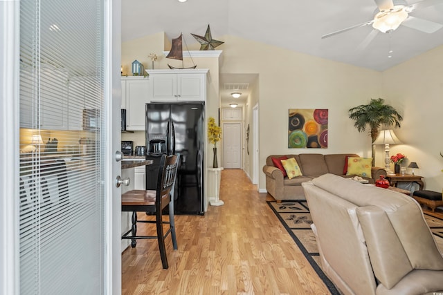 living room featuring ceiling fan, lofted ceiling, and light hardwood / wood-style floors