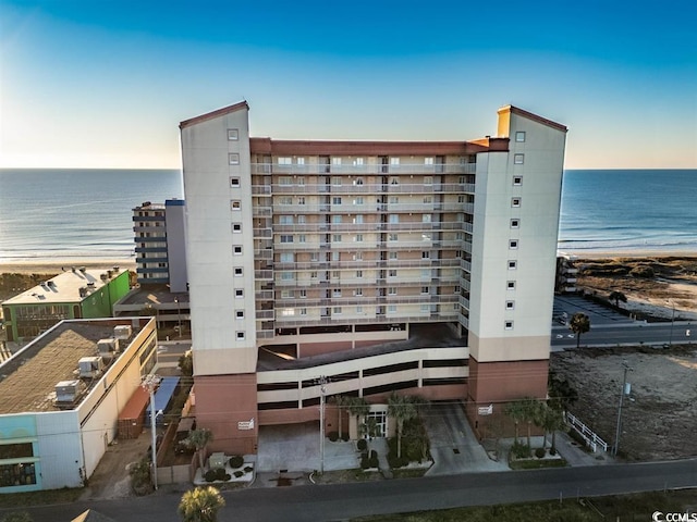 view of building exterior featuring a water view and a beach view