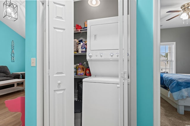 laundry room with ceiling fan and stacked washer / dryer