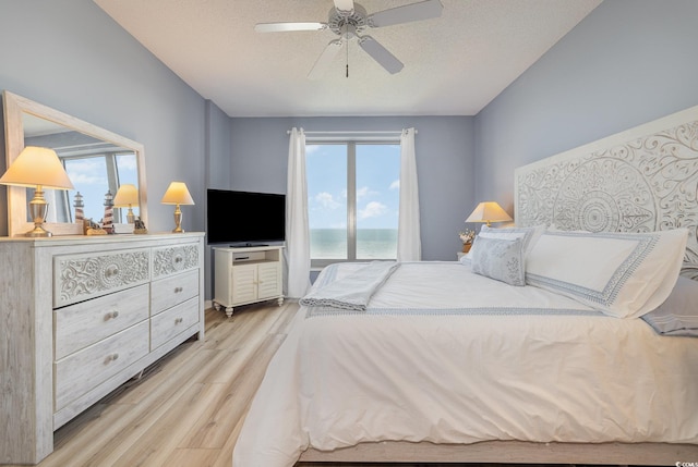 bedroom featuring ceiling fan, a textured ceiling, and light wood-type flooring