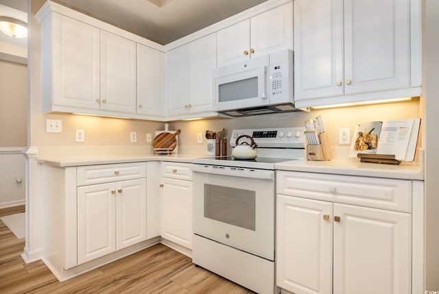 kitchen with white cabinetry, white appliances, and light hardwood / wood-style floors