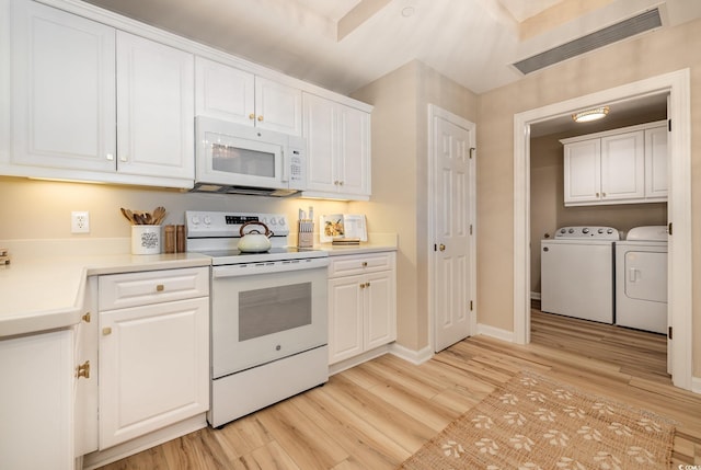 kitchen featuring white appliances, light wood-type flooring, washer and dryer, and white cabinets