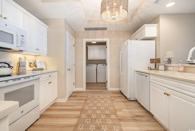 kitchen with white cabinetry, washer and dryer, white appliances, and light hardwood / wood-style floors