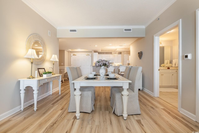 dining space with ornamental molding and light hardwood / wood-style floors