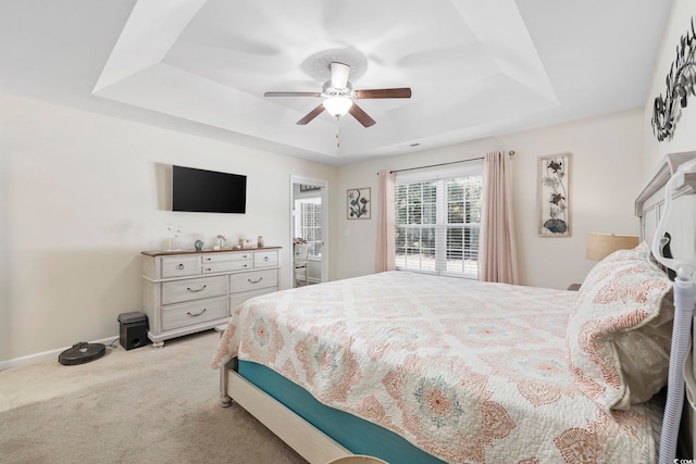 bedroom with light carpet, a raised ceiling, and ceiling fan