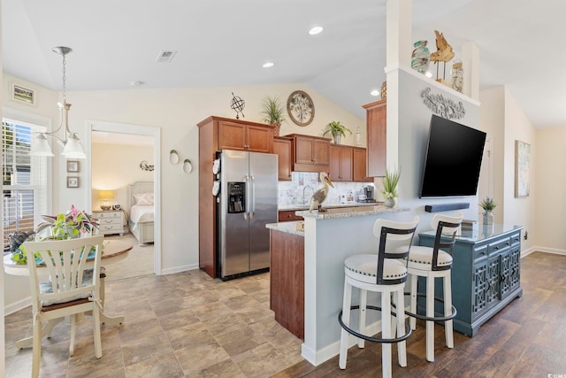 kitchen with vaulted ceiling, stainless steel fridge, backsplash, hanging light fixtures, and kitchen peninsula