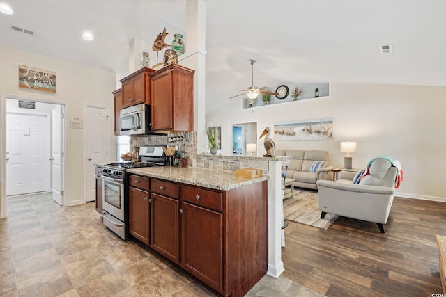 kitchen with appliances with stainless steel finishes, hardwood / wood-style floors, tasteful backsplash, ceiling fan, and light stone counters