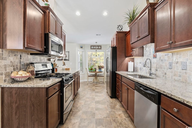 kitchen with stainless steel appliances, tasteful backsplash, light stone countertops, and sink