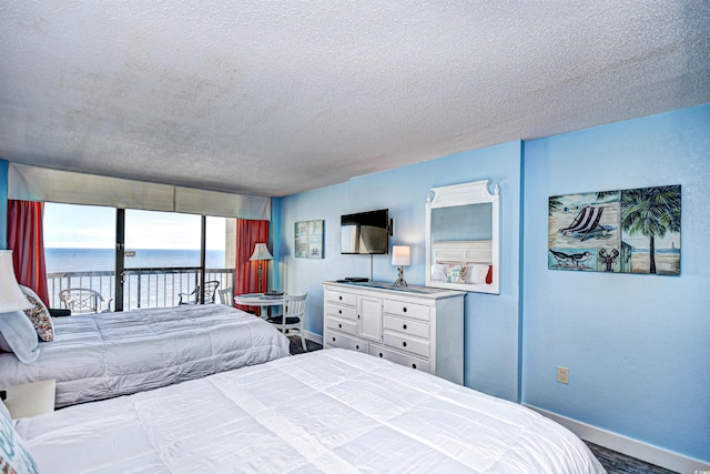 bedroom featuring access to outside, a textured ceiling, and a water view