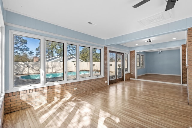 spare room with ceiling fan, brick wall, and light hardwood / wood-style floors