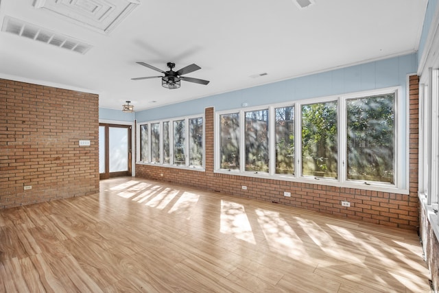 unfurnished living room with ceiling fan, brick wall, and light hardwood / wood-style flooring