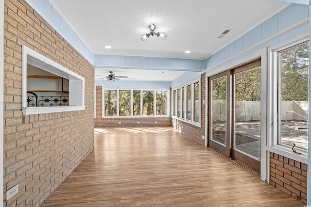 interior space featuring crown molding, brick wall, light hardwood / wood-style floors, and plenty of natural light