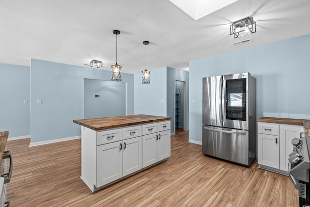 kitchen featuring pendant lighting, wooden counters, stainless steel refrigerator, white cabinetry, and light wood-type flooring