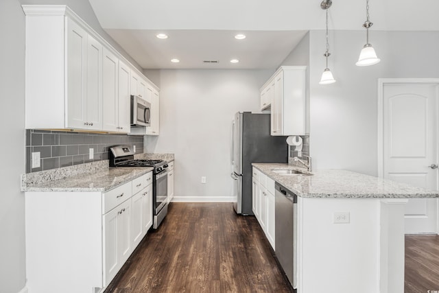 kitchen with appliances with stainless steel finishes, sink, pendant lighting, and white cabinets