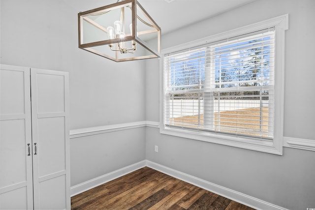 unfurnished dining area with a chandelier and dark hardwood / wood-style flooring