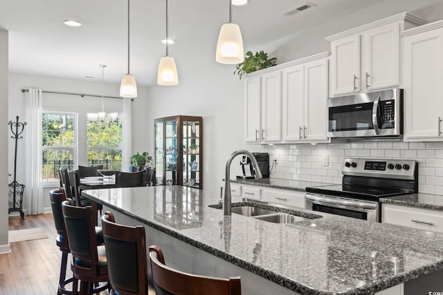 kitchen with sink, decorative light fixtures, stainless steel appliances, and white cabinets