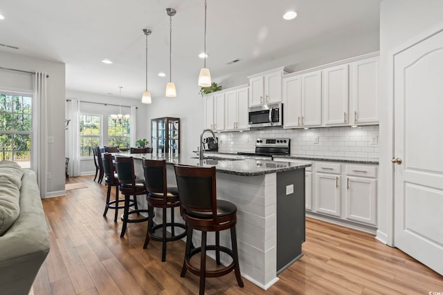 kitchen with sink, white cabinetry, an island with sink, pendant lighting, and stainless steel appliances