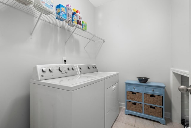 clothes washing area featuring washer and dryer and light tile patterned flooring