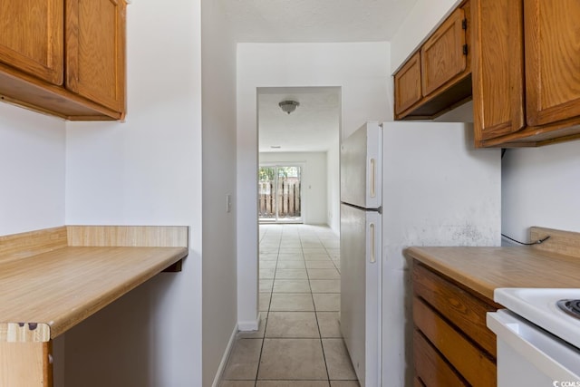 1025 Carolina Rd Unit I-7, Conway, SC 29526 - kitchen with light tile patterned floors, light countertops, brown cabinetry, and freestanding refrigerator