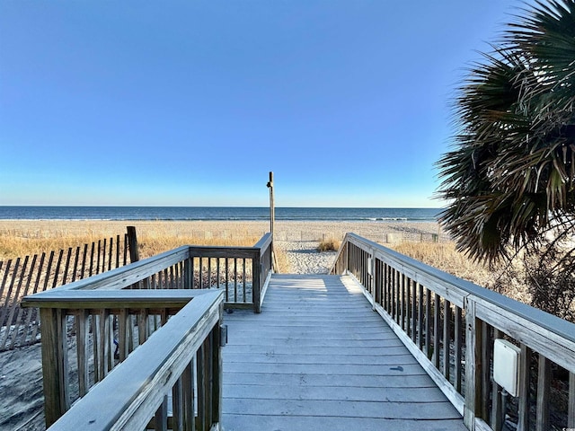 view of property's community with a beach view and a deck with water view