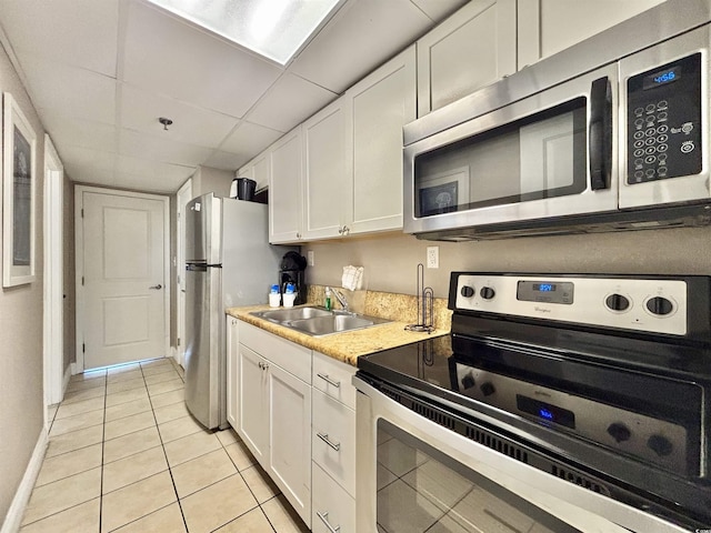 kitchen with sink, a paneled ceiling, stainless steel appliances, and white cabinets